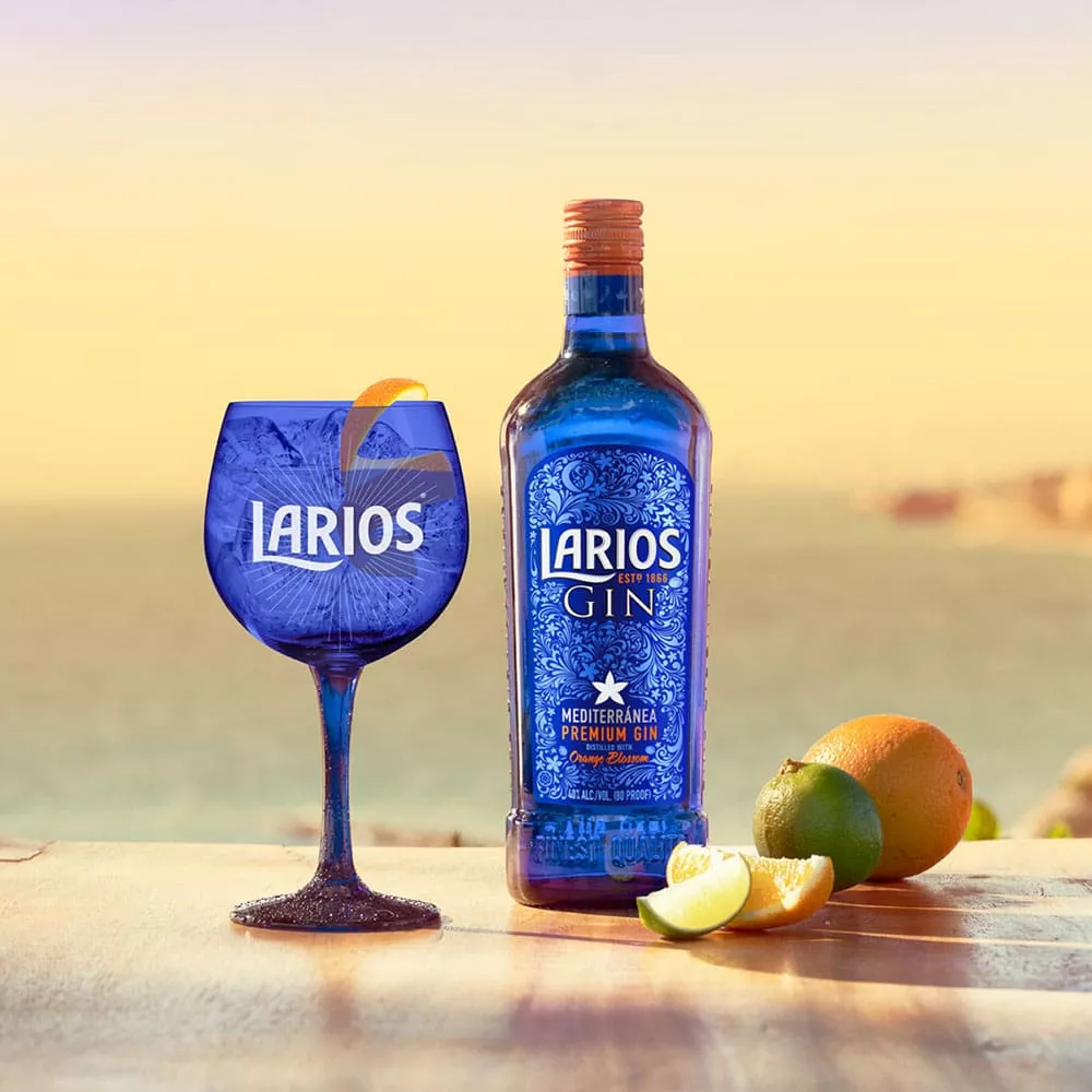 (Gallery_5) Alt: A blue bottle and glass of Larios gin served beside fresh oranges in the sunset | Filename:gin-bottle-glass-sunset-fresh-oranges.jpg