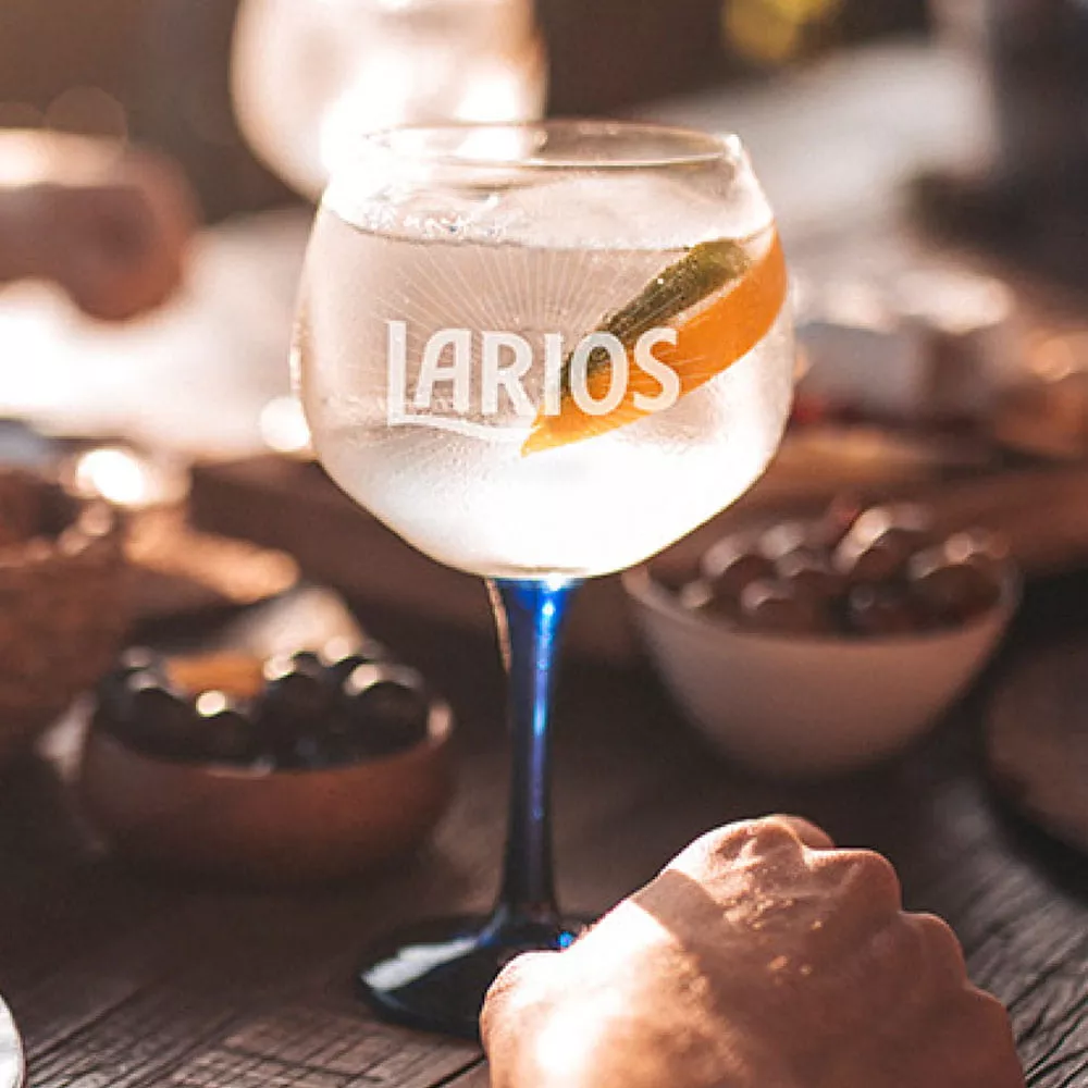 An iced glass of gin with orange garnish